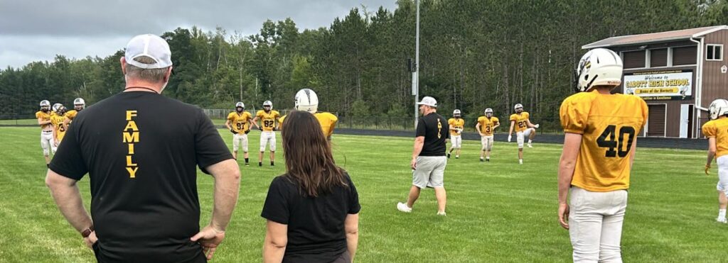 team on football field watched by coaches